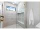 Stylish shower featuring grey marble-look tile, glass enclosure, window, and bench at 48 Sandpiper Rd, Tampa, FL 33609