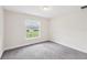 Bright bedroom features plush gray carpet and a sunlit window offering a pleasant neighborhood view at 5134 Jenson Ave, Spring Hill, FL 34608