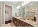 Bathroom with a double sink vanity with granite countertop, walk-in shower with marble tile, and green walls at 5910 La Rosa Ln, Apollo Beach, FL 33572