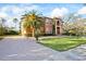 Elegant two-story home boasts a terracotta exterior, mature palms, a brick driveway, and manicured lawn at 5910 La Rosa Ln, Apollo Beach, FL 33572