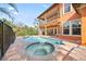 Tranquil pool and spa area surrounded by lush landscaping and an orange house with a patio at 5910 La Rosa Ln, Apollo Beach, FL 33572