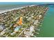 An aerial view of a waterfront neighborhood showcasing homes, the beach and the ocean, with an arrow highlighting the featured home at 720 Bay Esplanade, Clearwater Beach, FL 33767