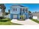 Inviting two-story stilt home with a spacious porch, staircase, and lush landscaping at 720 Bay Esplanade, Clearwater Beach, FL 33767