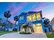 Charming two-story stilt home featuring a large porch and tropical landscaping, set against a twilight sky at 720 Bay Esplanade, Clearwater Beach, FL 33767