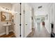 Hallway with wood-look floors, powder room, and view of living room with outdoor light at 720 Bay Esplanade, Clearwater Beach, FL 33767