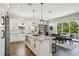 Bright eat-in kitchen featuring granite counters, wood floors, island with pendant lights, and an adjacent dining area with balcony access at 720 Bay Esplanade, Clearwater Beach, FL 33767