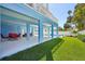 Blue-walled outdoor space with seating, a glimpse of the pool, and lush green lawn area at 720 Bay Esplanade, Clearwater Beach, FL 33767