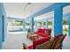 Blue walled outdoor lounge area featuring red upholstered seating and a view of the pool and greenery at 720 Bay Esplanade, Clearwater Beach, FL 33767