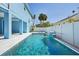 Inviting in-ground pool with waterfall feature, surrounded by a white fence and landscaping, perfect for relaxation and backyard enjoyment at 720 Bay Esplanade, Clearwater Beach, FL 33767