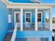 Inviting front porch with seating, white pillars, and bright blue siding, offering a cozy outdoor space at 720 Bay Esplanade, Clearwater Beach, FL 33767