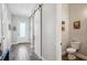 Powder room featuring toilet, art, and a hall view with a sliding barn door at 720 Bay Esplanade, Clearwater Beach, FL 33767