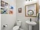Powder room with pedestal sink, gold-framed mirror, toilet, and coastal-themed decor at 720 Bay Esplanade, Clearwater Beach, FL 33767