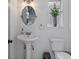 Bright bathroom with pedestal sink, oval mirror, and a charming window with a plant at 9067 Cypress Trl, Seminole, FL 33777