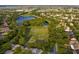 Discover an aerial view featuring a well-maintained community park, lake, and soccer field, surrounded by lush trees and nearby homes at 12339 Silton Peace Dr, Riverview, FL 33579