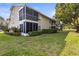 The backyard features lush green grass, manicured hedges, and screened-in patio on upper and lower levels at 12411 Eagleswood Dr # B, Hudson, FL 34667