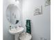Simple half bathroom featuring a pedestal sink, round mirror, and seashell-themed wall art at 14422 Scottburgh Glen Dr, Wimauma, FL 33598