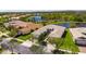 Aerial view of beige single Gathering home with red roof tiles next to a lake surrounded by trees at 15657 Aurora Lake Cir, Wimauma, FL 33598