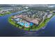 An aerial view of community pool, clubhouse, tennis and pickle ball courts near a lake at 15657 Aurora Lake Cir, Wimauma, FL 33598