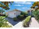Beige single Gathering home with paver driveway, landscaping and front entrance portico with white columns at 15657 Aurora Lake Cir, Wimauma, FL 33598