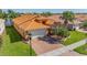 Beautiful exterior of home with an orange tile roof, brick driveway, green grass and palm trees at 16021 Golden Lakes Dr, Wimauma, FL 33598