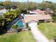 Aerial front view showcasing home with screened pool, lush lawn, and a convenient two-car garage at 1830 Oak Forest S Dr, Clearwater, FL 33759