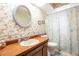 Bathroom featuring a wood vanity, round mirror and floral wallpaper at 1830 Oak Forest S Dr, Clearwater, FL 33759