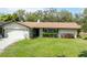 Traditional single-story home with a well-kept lawn, attached garage, and mature shrubbery at 1830 Oak Forest S Dr, Clearwater, FL 33759