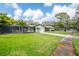 Charming home with lush landscaping, a screened-in lanai, and a long driveway at 1830 Oak Forest S Dr, Clearwater, FL 33759