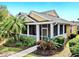 Charming yellow home featuring a screened porch and beautifully landscaped front yard with vibrant plants and palm trees at 203 Oceania Ct, Apollo Beach, FL 33572