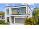 Modern two-story home featuring clean lines, a gray garage door, and tropical landscaping at 2519 N Riverside Dr, Tampa, FL 33602