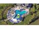Aerial view of a resort-style pool with a slide, lounge area, and lush tropical landscaping at 30226 Merilee Pl, Wesley Chapel, FL 33545