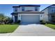 Two-story home featuring a spacious two car garage, concrete driveway, and manicured landscaping at 30226 Merilee Pl, Wesley Chapel, FL 33545