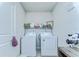 Bright laundry room features white washer and dryer with storage at 30226 Merilee Pl, Wesley Chapel, FL 33545