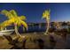 Backyard waterfront seating area at night with palm trees, tropical decor and a view of the bay at 351 S Julia Cir, St Pete Beach, FL 33706