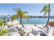 Relaxing waterfront view with white sand, palm trees, Adirondack chairs, and a private boat dock at 351 S Julia Cir, St Pete Beach, FL 33706
