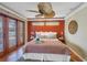 Well-lit bedroom with a ceiling fan, brick-red accent wall, and sliding doors to an outside patio area at 351 S Julia Cir, St Pete Beach, FL 33706