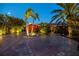 Beautifully illuminated driveway showcases brick pavers and lush, tropical landscaping leading to a charming home at 351 S Julia Cir, St Pete Beach, FL 33706
