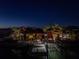 Nighttime view of waterfront home, showcasing boat dock, palm trees and tiki style covered patio at 351 S Julia Cir, St Pete Beach, FL 33706