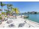Beautiful waterfront view with a sandy beach area, dock, and tropical landscaping at 351 S Julia Cir, St Pete Beach, FL 33706