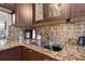 Close-up of kitchen with brown cabinets, granite countertops, and stainless steel sink at 6800 20Th N Ave # 309, St Petersburg, FL 33710