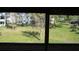 A view from the enclosed sunroom to the grassy outdoor space beyond at 8455 112Th St # 202, Seminole, FL 33772