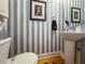 Stylish powder room with gray and white striped walls, pedestal sink, and decorative artwork at 849 3Rd N St, St Petersburg, FL 33701