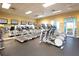 Modern gym with treadmills, elliptical machines, and floor-to-ceiling windows for a refreshing workout at 9296 Gladsome Dr, Land O Lakes, FL 34637