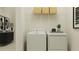 Well-lit laundry room with washer, dryer, wire shelving, and modern decorations at 9296 Gladsome Dr, Land O Lakes, FL 34637