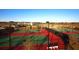 Aerial view of tennis and basketball courts, fenced-in with professional lighting and resort buildings in the background at 9296 Gladsome Dr, Land O Lakes, FL 34637