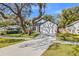 Beautiful home with a manicured front lawn, mature trees, and a long driveway leading to the garage at 9310 N Willow Ave, Tampa, FL 33612