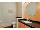 Elegant powder room featuring black granite countertop, sleek fixtures, and patterned wallpaper at 950 Monterey Ne Pt, St Petersburg, FL 33704