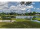 Relaxing view of the community pond with fountain, surrounded by green grass and mature trees at 9845 84Th Way, Seminole, FL 33777