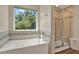 Bathroom view featuring a standalone tub, tiled shower, and a window with a view of trees at 11486 June Briar Loop, San Antonio, FL 33576