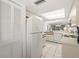 Bright kitchen featuring white appliances and cabinets, skylight, and easy access to living areas at 1728 Golfview Dr # 1728, Tarpon Springs, FL 34689